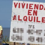 Un hombre camina junto a un cartel de viviendas en alquiler en A Mariña (Lugo)