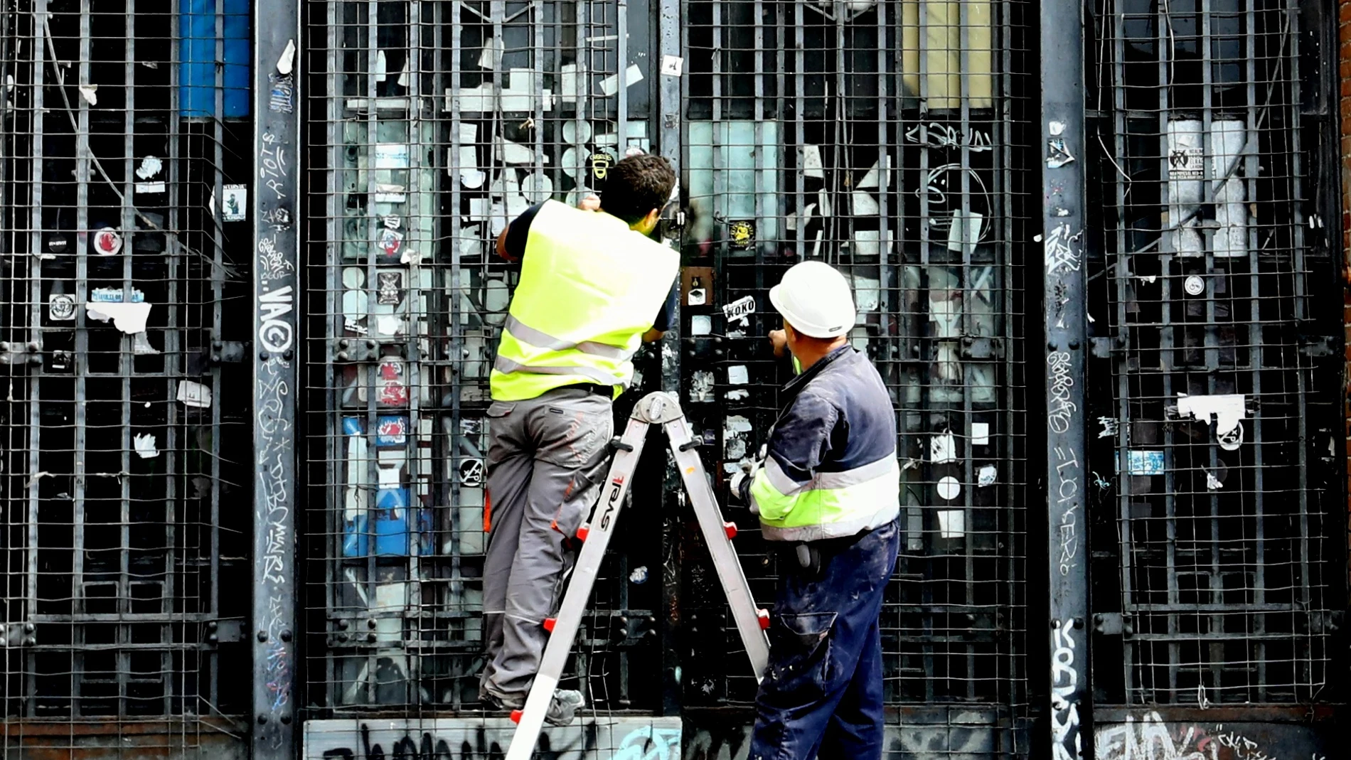 Dos operarios colocan unas nuevas cerraduras para evitar una nueva okupación en un edificio de Madrid