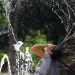 Una chica se refresca en una de las fuentes de la ciudad, para aliviar las altas temperaturas. EFE/Salas