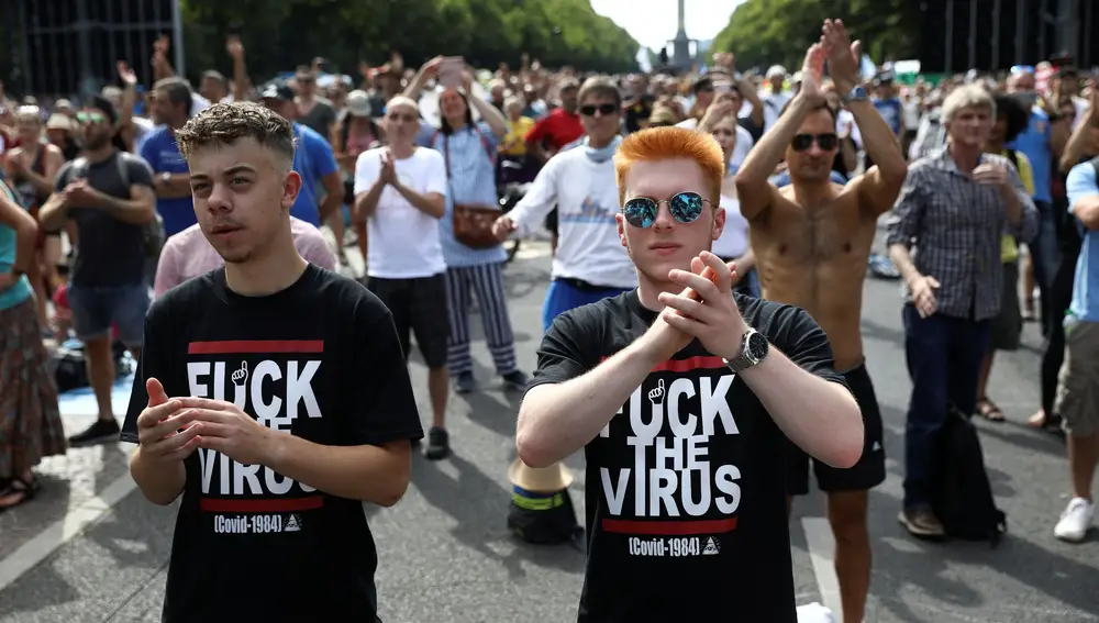 Dos manifestantes aplauden durante la marcha contra las medidas impuestas por el coronavirus en Berlín