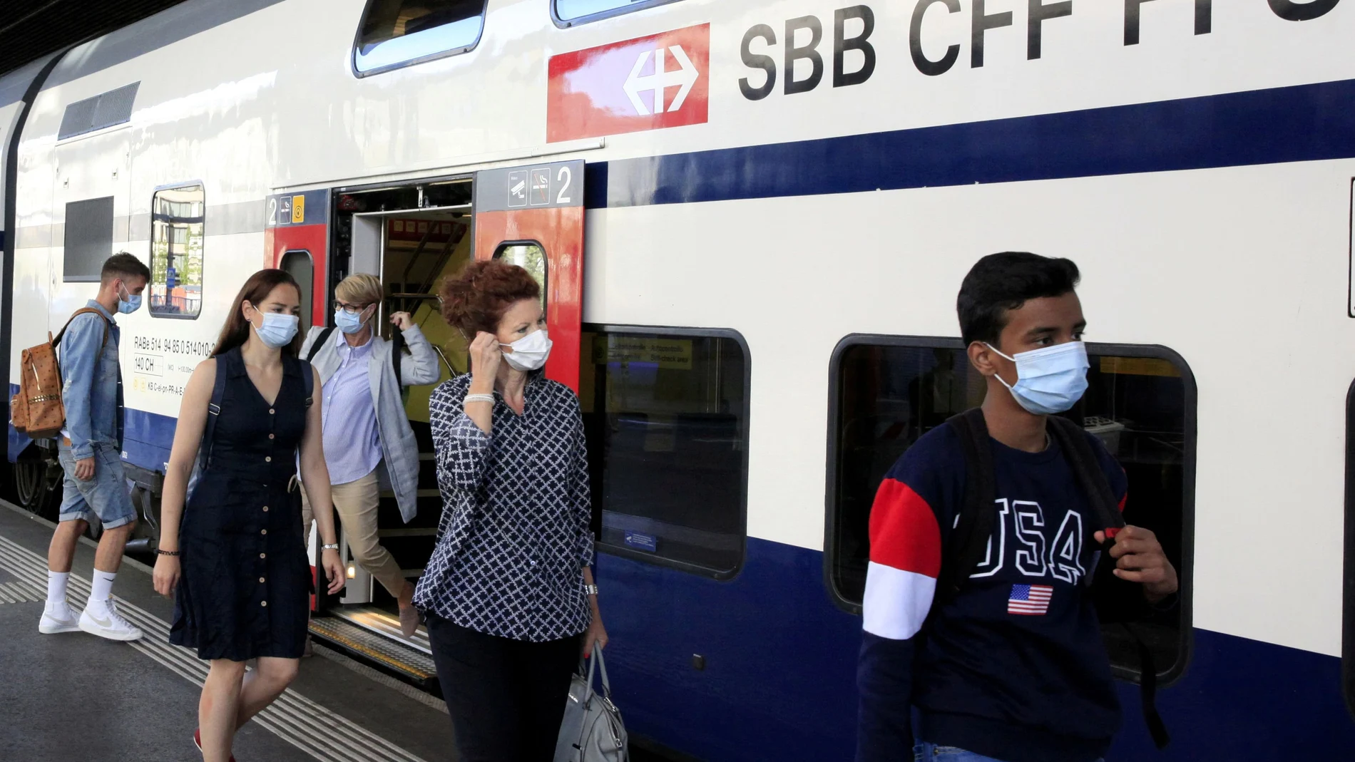 FILE PHOTO: Passengers wear protective masks as they leave a train of Swiss railway operator SBB in Zurich, Switzerland