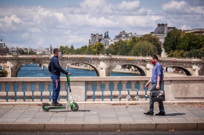 Varios parisinos con mascarilla atraviesan uno de loa numerosos puentes que unen el río Sena