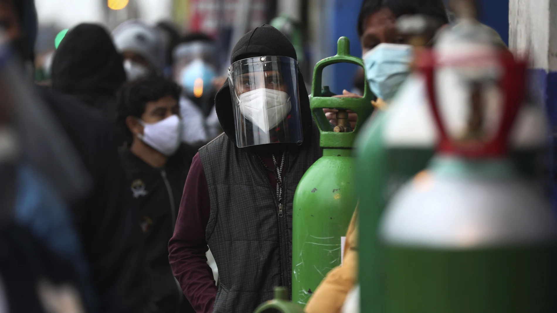 People wait in line with their empty oxygen cylinders to refill at a shop in the San Juan neighborhood of Lima, Peru, Monday, Aug. 3, 2020. Peruvian authorities calculate that more than a quarter of Limaâ€™s population may have been infected with the new coronavirus, and Peru has the highest death rate per million in the Americas. (AP Photo/Martin Mejia)