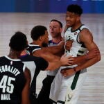 Giannis Antetokounmpo tienen que ser sujetado para no responder al empujón de Donta Hall.