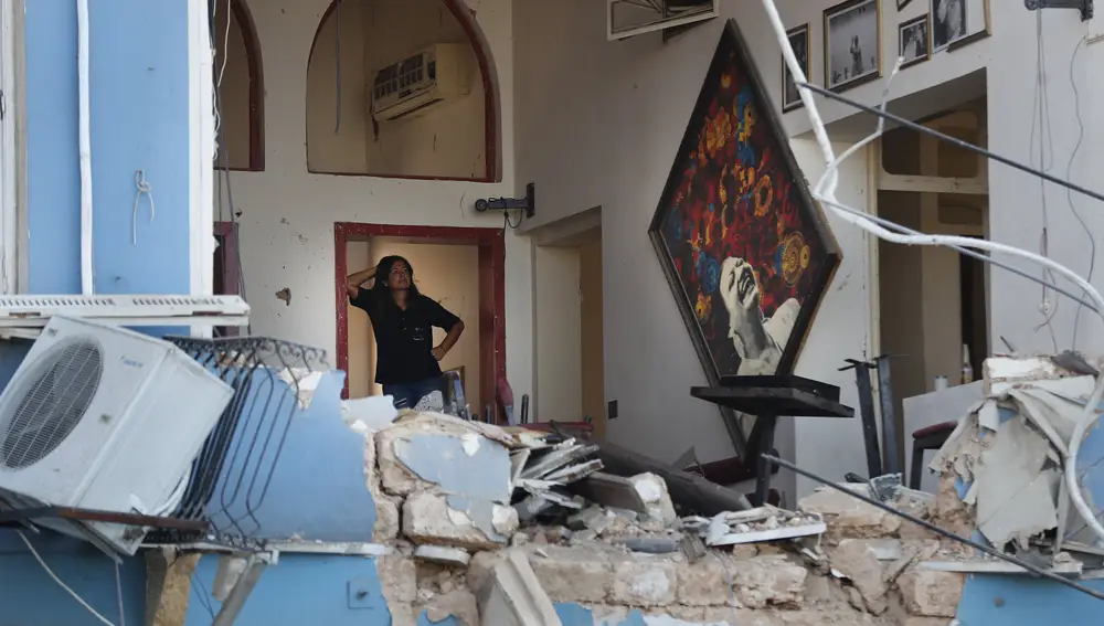 Una mujer observa los daños en su restaurante, cercano al puerto de Beirut