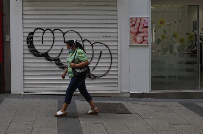 Una mujer pasa por delante de una tienda cerrada durante el confinamiento
