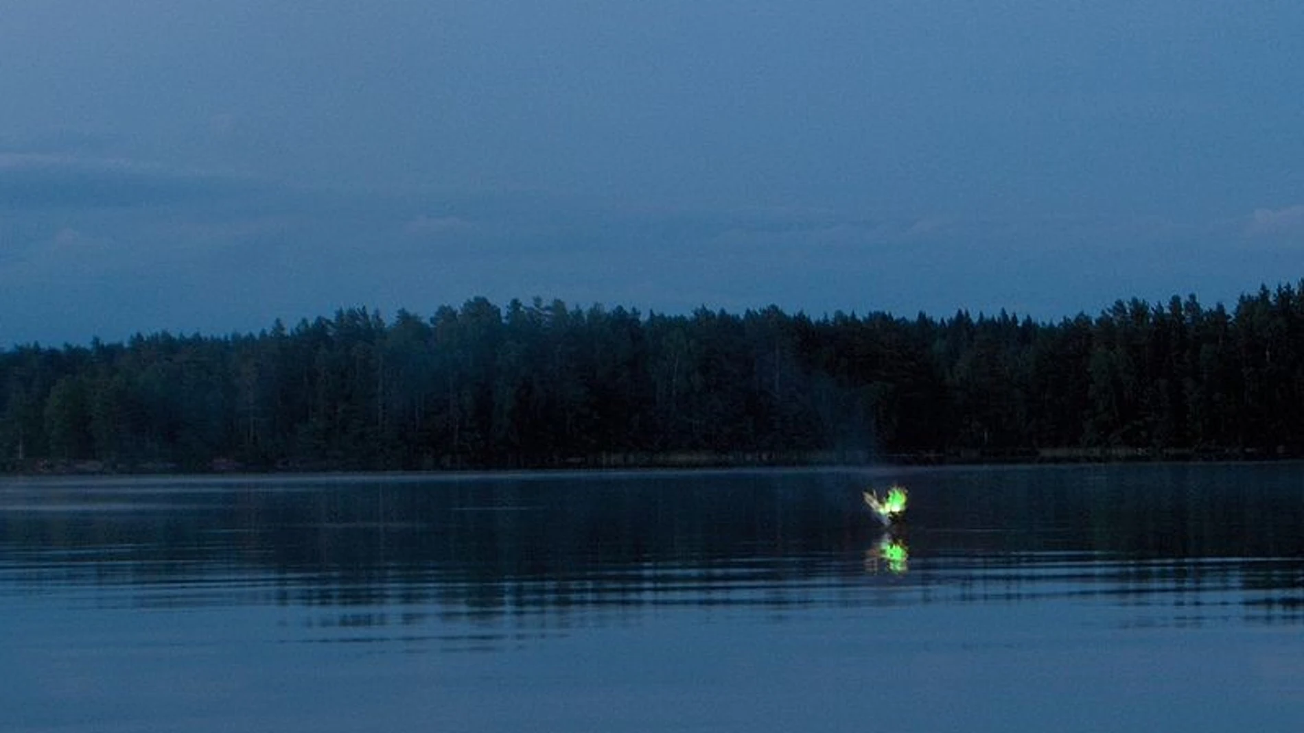 Recreación fotográfica de un fuego fatuo editando el color de una hoguera de corteza de abedul flotando sobre el agua.