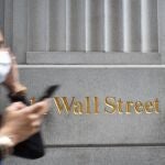 Una mujer con mascarilla pasea por Wall Street, donde tiene su sede la bolsa de Nueva York