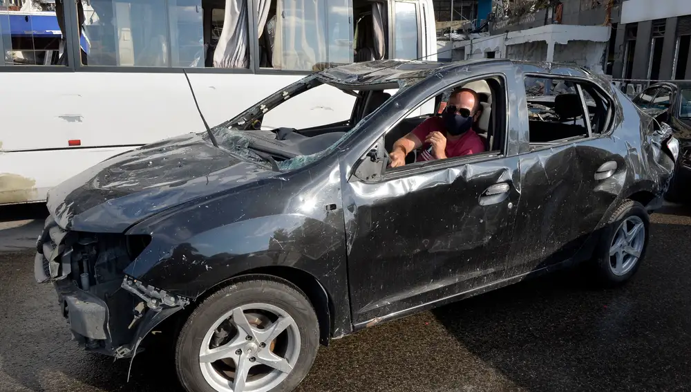 Un hombre acude en lo que le queda de coche a la manifestación antigubernamental una semana después de la explosión