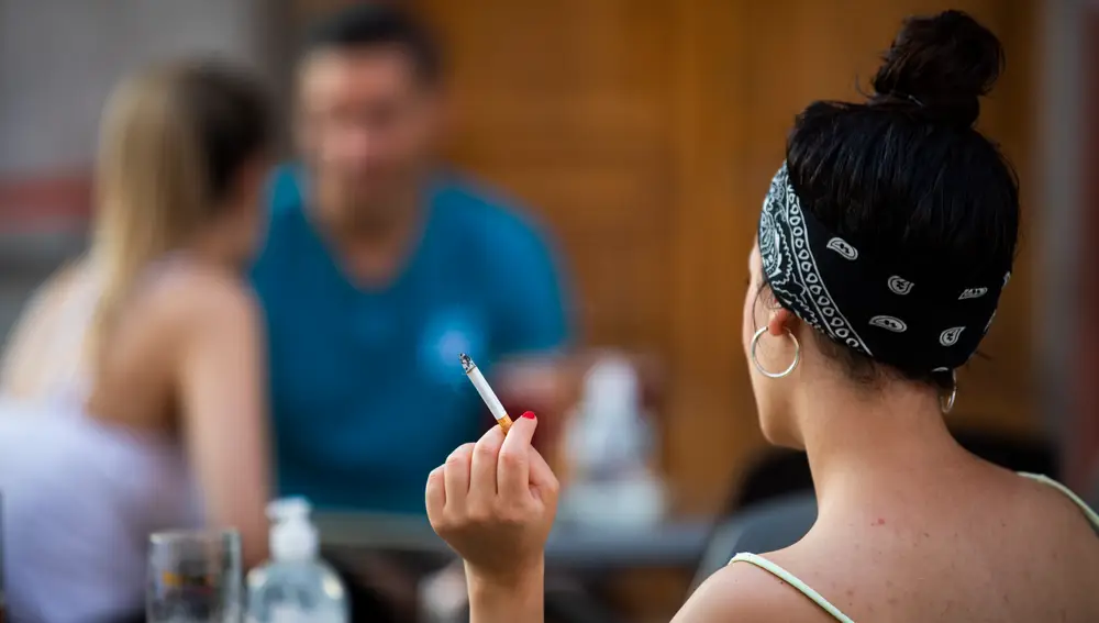 Terrazas en La Latina de Madrid con gente tomando algo con mascarillas. en el brazo. Unas chicas fumando en la terraza.