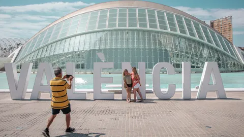 Dos personas se fotografían frente a l'Hemisfèric de la Ciudad de las Artes y las Ciencias de València