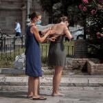 Dos turistas se aplican crema solar en una plaza del centro histórico de Valencia