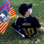 Un joven aficionado con una camiseta de Messi y una bandera del Barça con el rostro de Bartomeu tachado