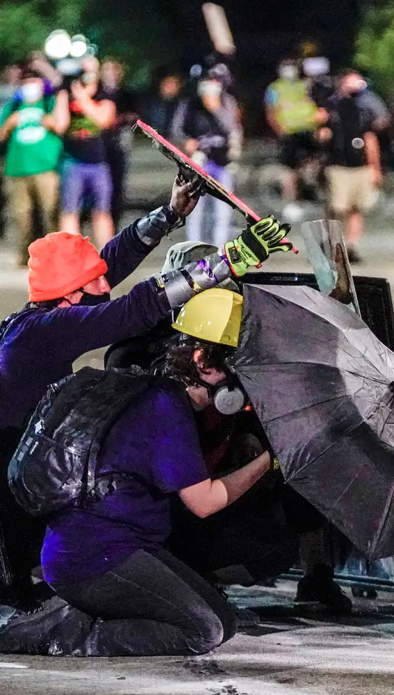 Manifestantes se protegen con un paraguas mientras se recrudecen los enfrentamientos con la Policía en Wisconsin