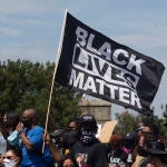 Participantes portan una mandera del movimiento «Black Lives Matter» contra el abuso policial a los negros