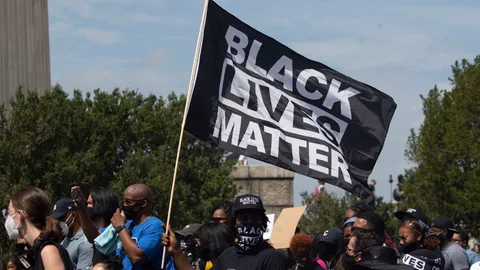 Participantes portan una mandera del movimiento «Black Lives Matter» contra el abuso policial a los negros