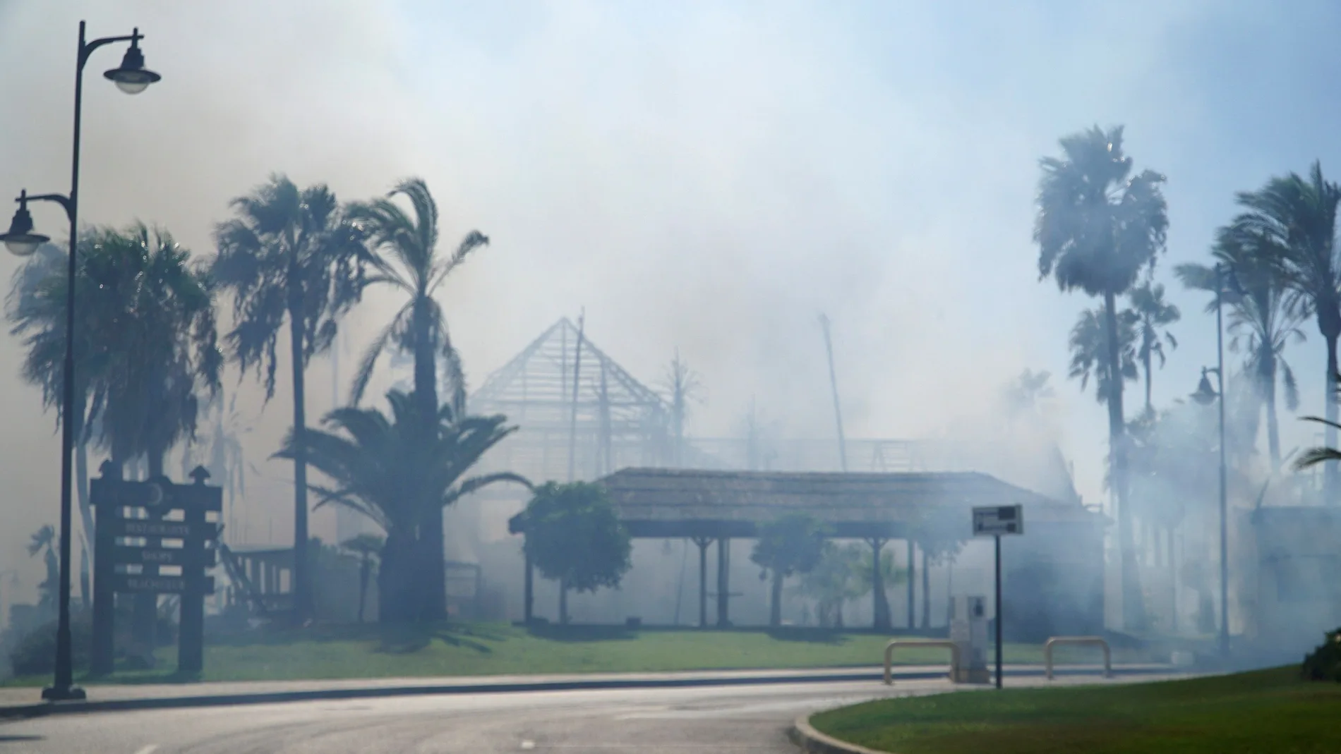 La entrada del centro comercial de lujo Laguna Village ubicado en la zona de Estepona, envuelta en llamas