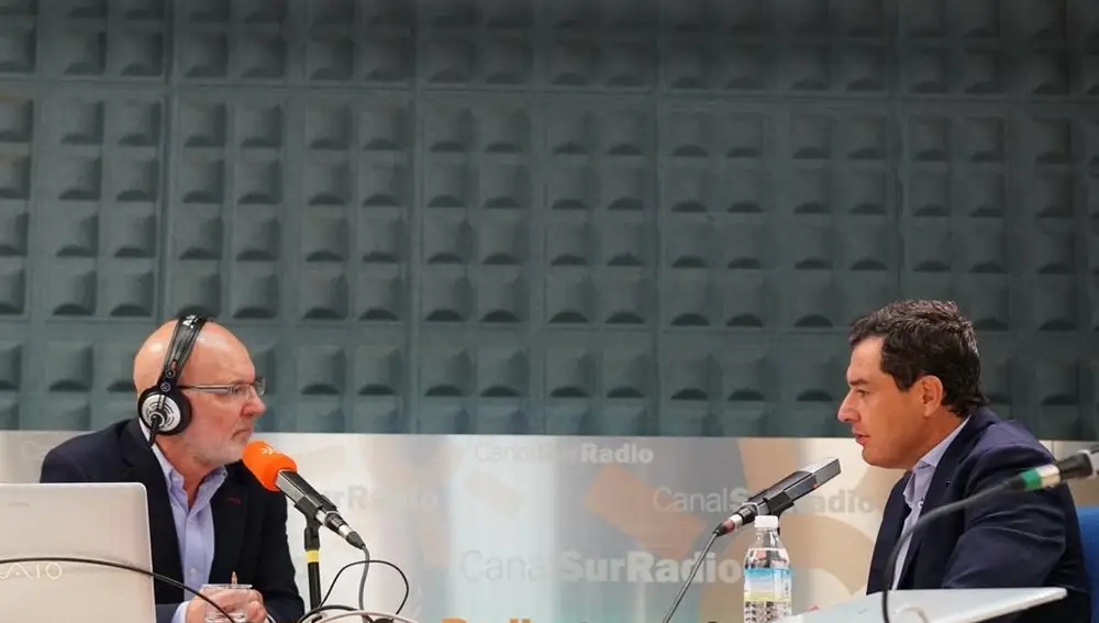 El presidente de la Junta de Andalucía, Juanma Moreno (d.), durante la entrevista, este lunes, con el periodista Jesús Vigorra (i.)