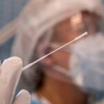 Una enfermera sostiene un bastoncillo mientras realiza una prueba PCR