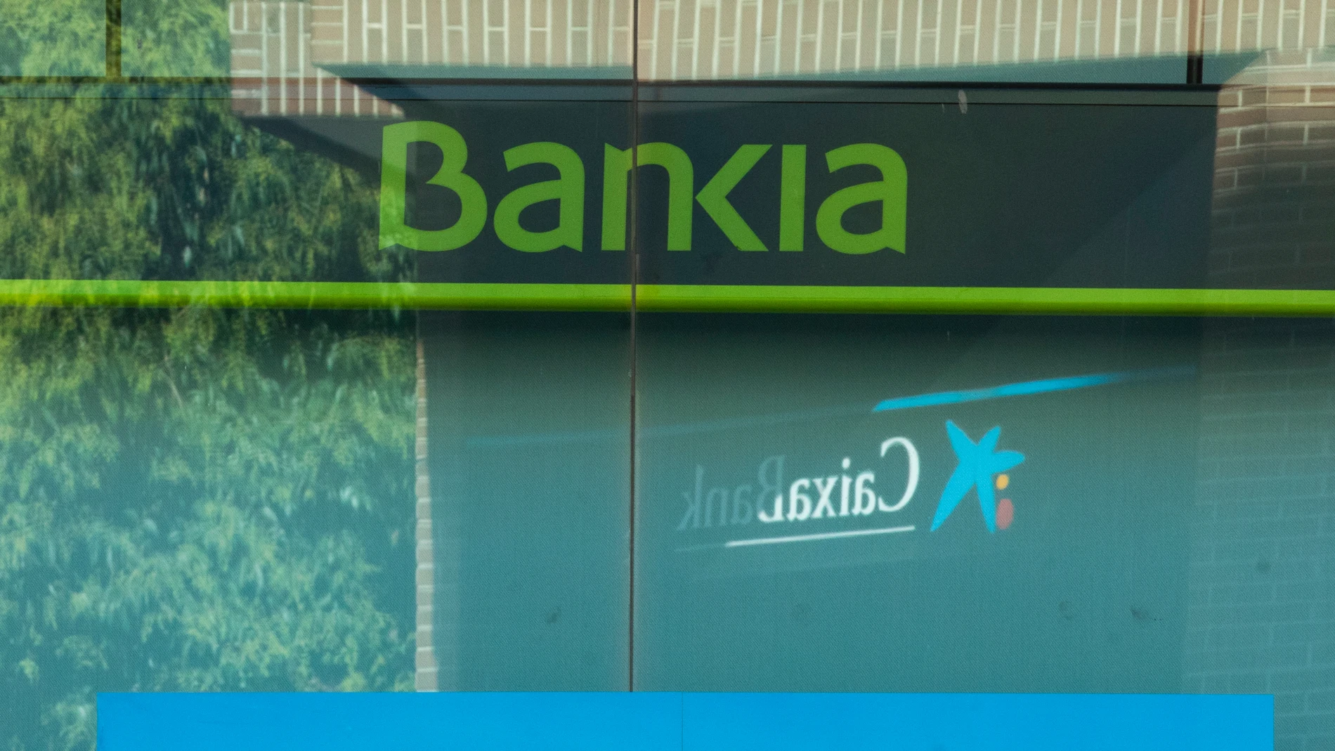 Imágenes de una sucursal bancaria de Bankia en la que se ve de fondo una de La Caixa por su inminente fusión.