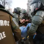 Carabineros retienen a una mujer con la que forcejeaban durante una concentración de manifestantes en Santiago de Chile
