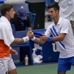 Pablo Carreño y Djokovic se saludan en el partido que jugaron hace un mes en el US Open, que terminó con la descalificación del serbio por dar un pelotazo a una juez de línea