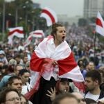 Una mujer cubierta con la bandera de Bielorrusia se manifiesta contra Lukashenko en Minsk