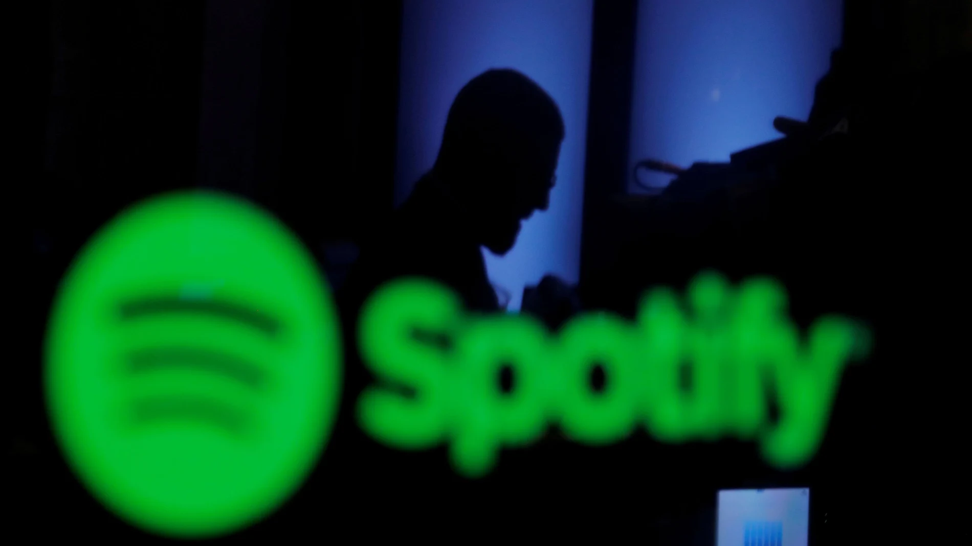 A trader is reflected in a computer screen displaying the Spotify brand before the company begins selling as a direct listing on the floor of the New York Stock Exchange in New York.