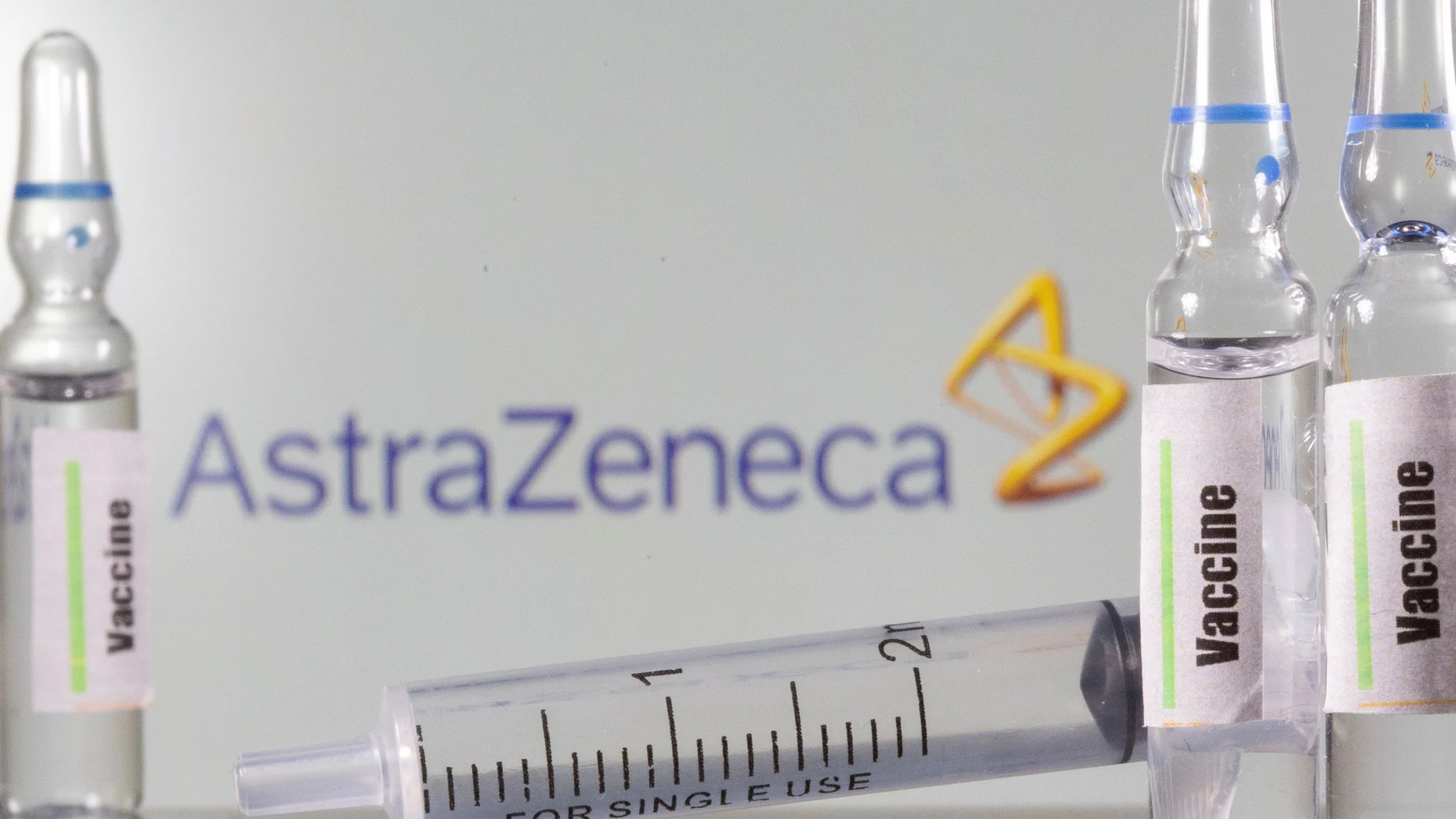 A test tube labelled with the Vaccine is seen in front of AstraZeneca logo in this illustration taken