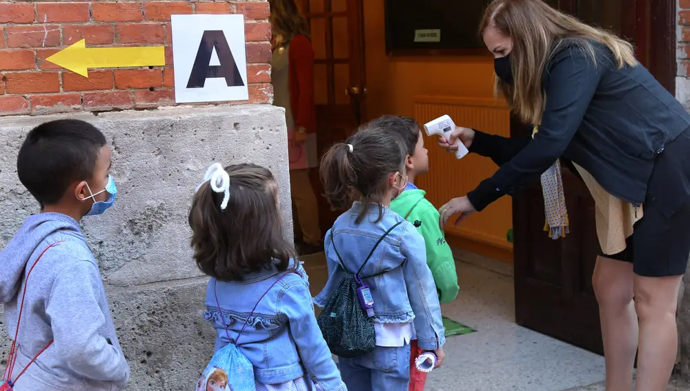 Una profesora toma la temperatura a varios escolares a la entrada de un centro educativo en Palencia