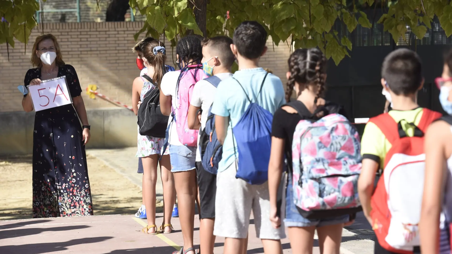 Alumnos de un colegio de Sevilla hacen cola ante una profesora