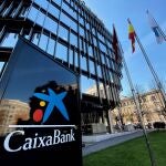 Panel vertical con el logo de Caixa Bank junto a la fachada acristalada de la Sede Central Caixa Bank en Madrid