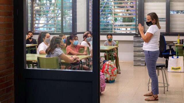 Una profesora da la bienvenida a sus alumnos en la Escola Catalonia de Barcelona, con los alumnos con mascarillas. EFE/Enric Fontcuberta