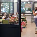 Una profesora da la bienvenida a sus alumnos en la Escola Catalonia de Barcelona, con los alumnos con mascarillas. EFE/Enric Fontcuberta