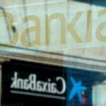 Los logos de Bankia y CaixaBank reflejados en un escaparate en Barcelona