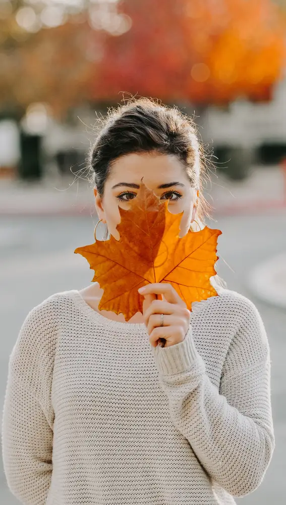 Una mujer ocultando su rostro en otoño.