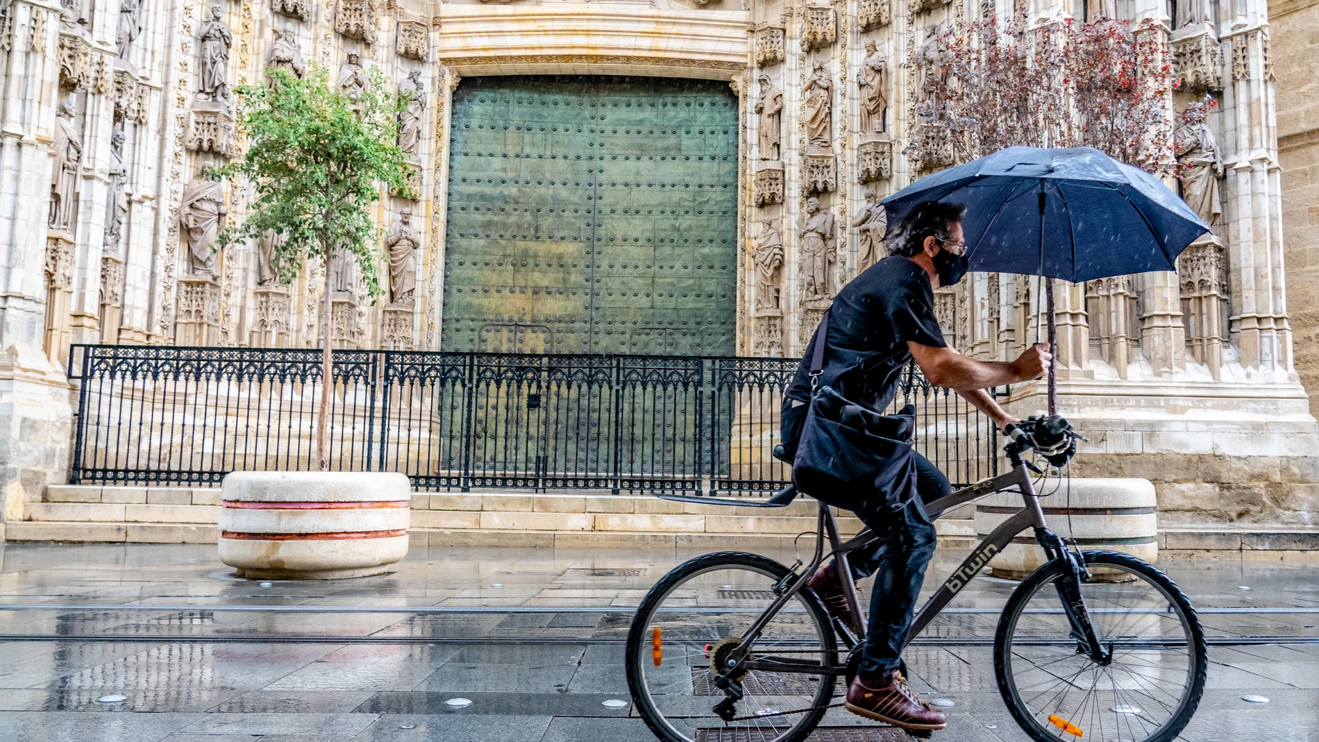Un ciclista paraguas por la Av. de la Constitución, en una mañana lluviosa en Sevilla a 18 de septiembre 2020