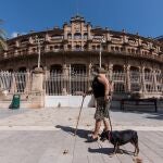 PALMA DE MALLORCA, 19/09/2020.- Una mujer pasea a su perro delante de la plaza de toros de Palma durante el primer día de las nuevas medidas de confinamiento y "nuevas restricciones" de movilidad en los barrios más afectados por la covid-19. -EFE/Atienza