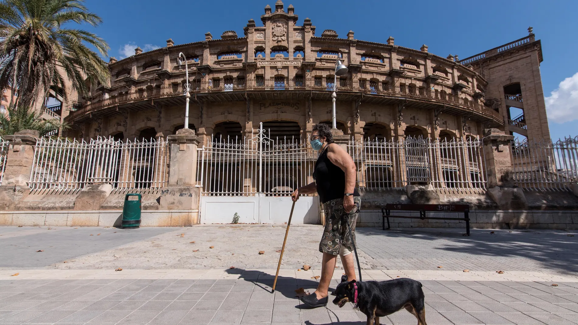 PALMA DE MALLORCA, 19/09/2020.- Una mujer pasea a su perro delante de la plaza de toros de Palma durante el primer día de las nuevas medidas de confinamiento y "nuevas restricciones" de movilidad en los barrios más afectados por la covid-19. -EFE/Atienza