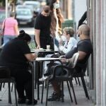 Un camarero atiende a unas personas sentadas en la terraza de un bar de Vallecas