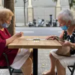 Dos mujeres mayores juegan a las cartas en una terraza