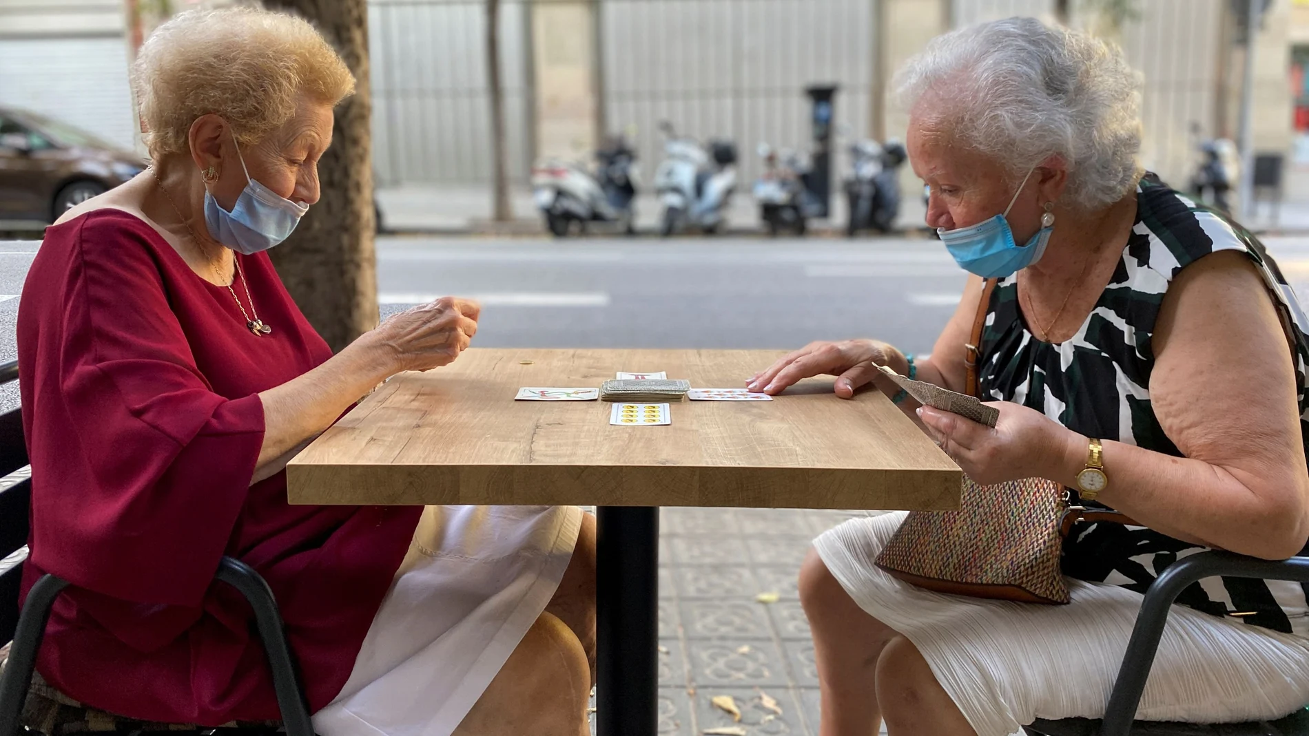 Dos mujeres mayores juegan a las cartas en una terraza