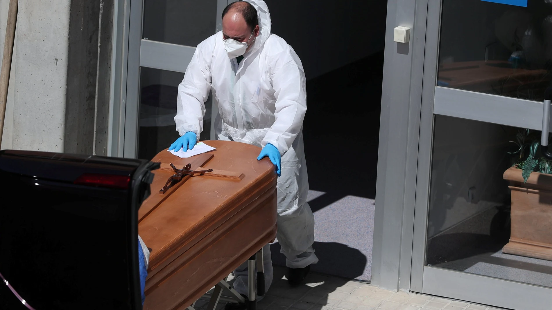 Un empleado de la funeraria con equipo de protección traslada un féretro en la morgue del hospital Severo Ochoa de Leganés