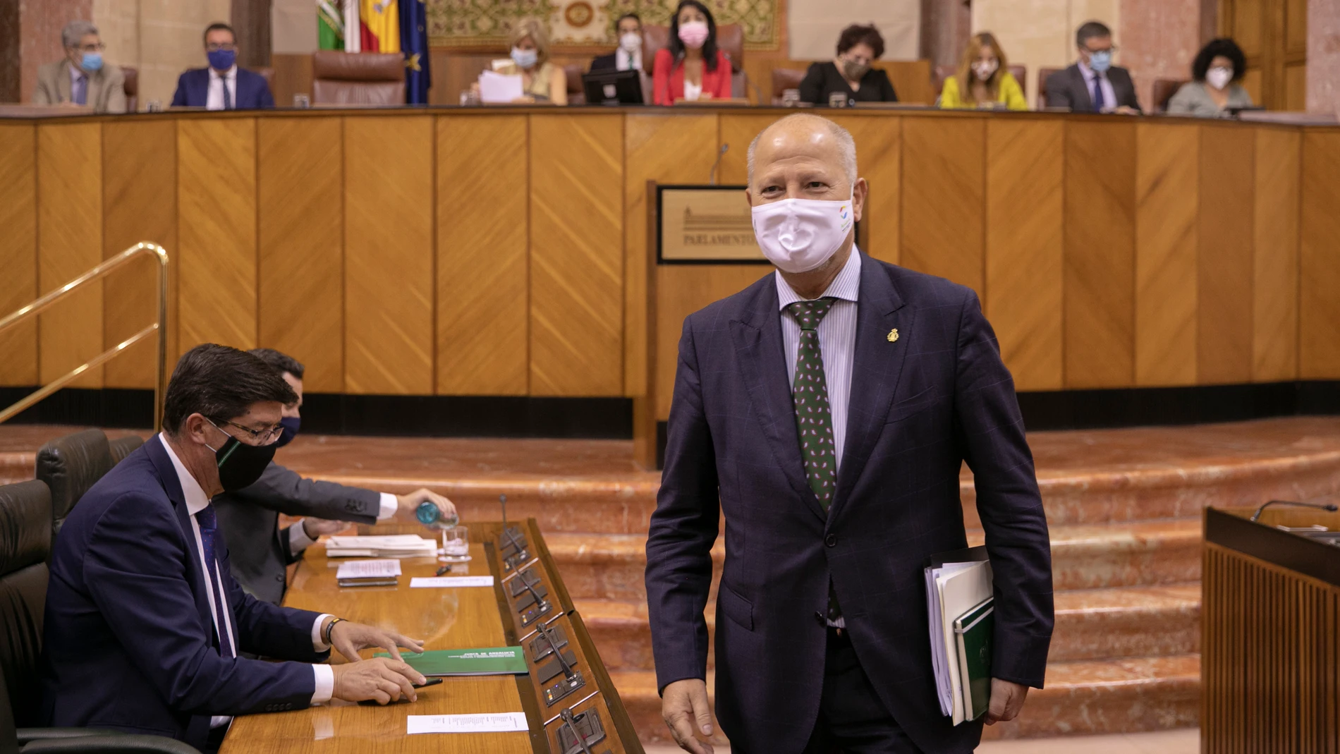 El presidente de la Junta de Andalucía, Juanma Moreno (1i), junto al vicepresidente de la Junta, Juan Marín (2i), tras saludar al consejero de educación, Javier Imbroda (d), antes del comienzo de la sesión de control al gobierno en el Pleno del Parlamento de Andalucía