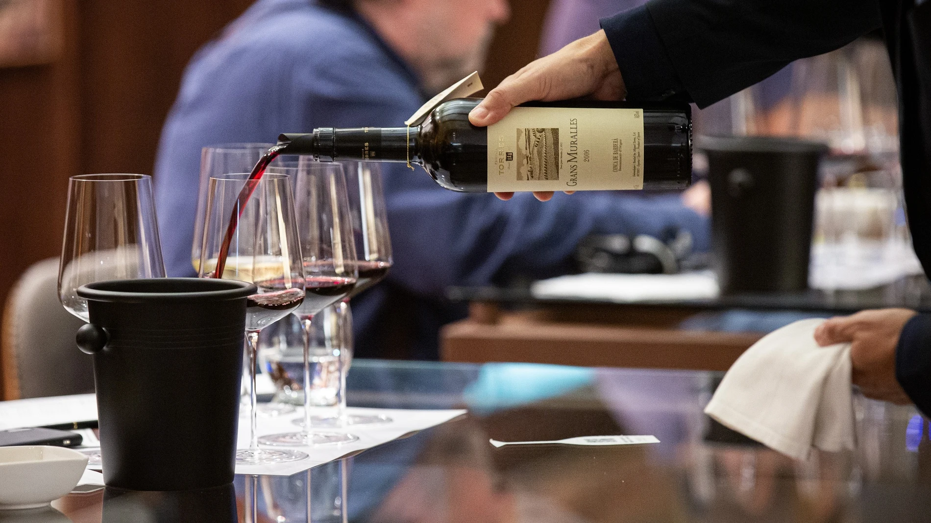 Un camarero sirve una copa de un Grans Muralles 2016 de la bodega Torres