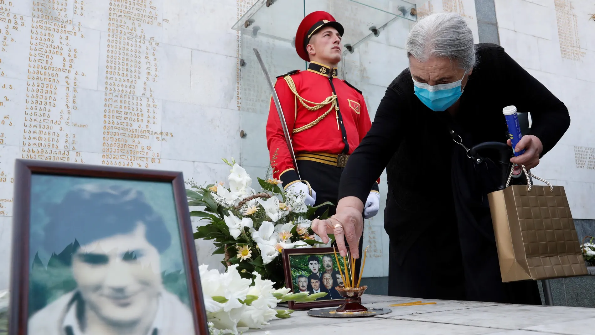 Una anciana coloca con cuidado objetos el monumento a los georgianos muertos durante el conflicto armado entre Georgia y Abjasia de 1992-1993