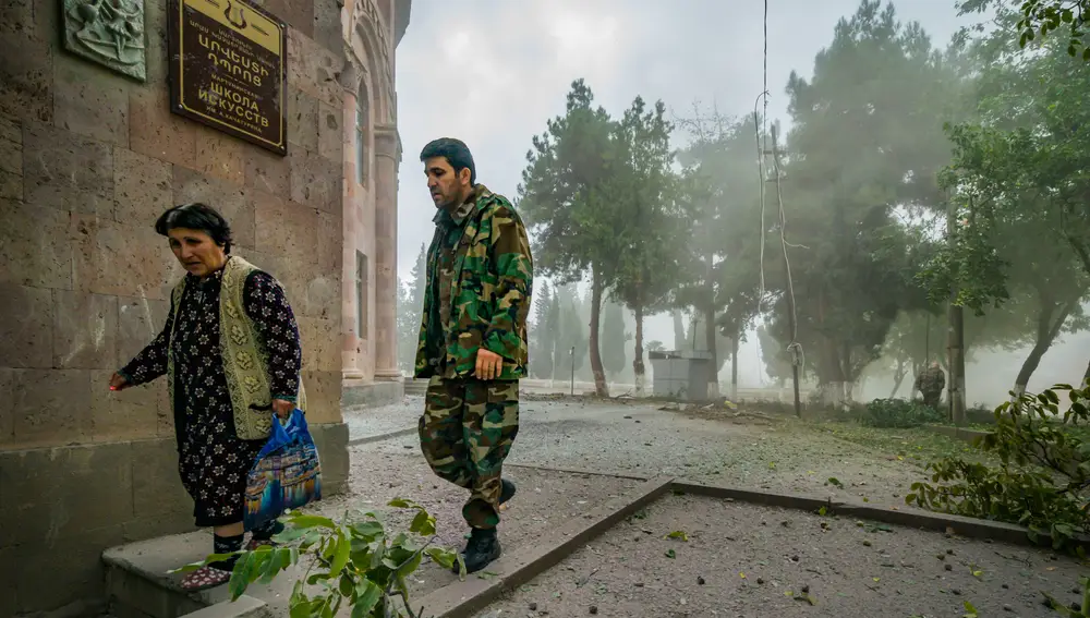 01 October 2020, Azerbaijan, Martuni: Un soldado acompaña a una mujer a cubierto durante los bombardeos sobre la ciudad de Martuni.