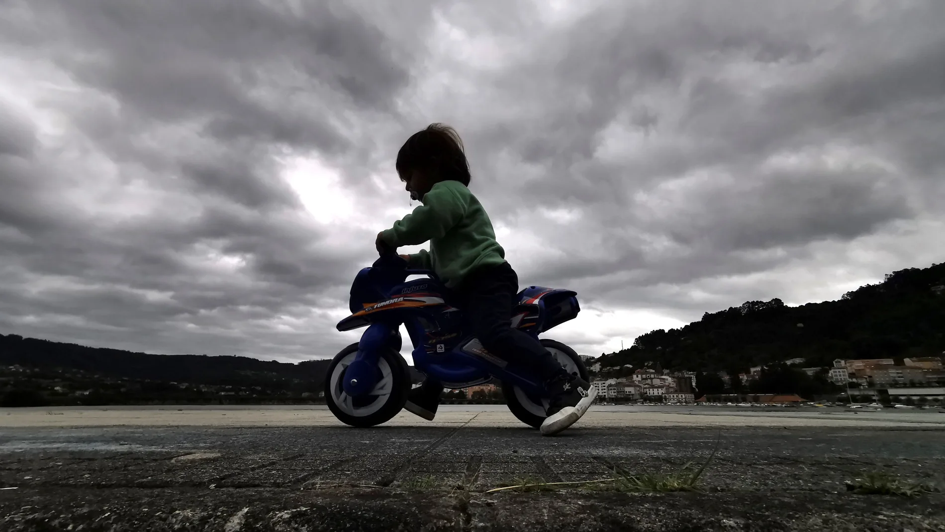 En la imagen un niño montaba en una moto de juguete por el paseo marítimo de Cabanas, en A Coruña. EFE/ Cabalar