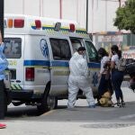 Un trabajado sanitario asiste a dos mujeres al ingresar a una ambulancia frente a la Clínica Popular de Catia, en Caracas (Venezuela).