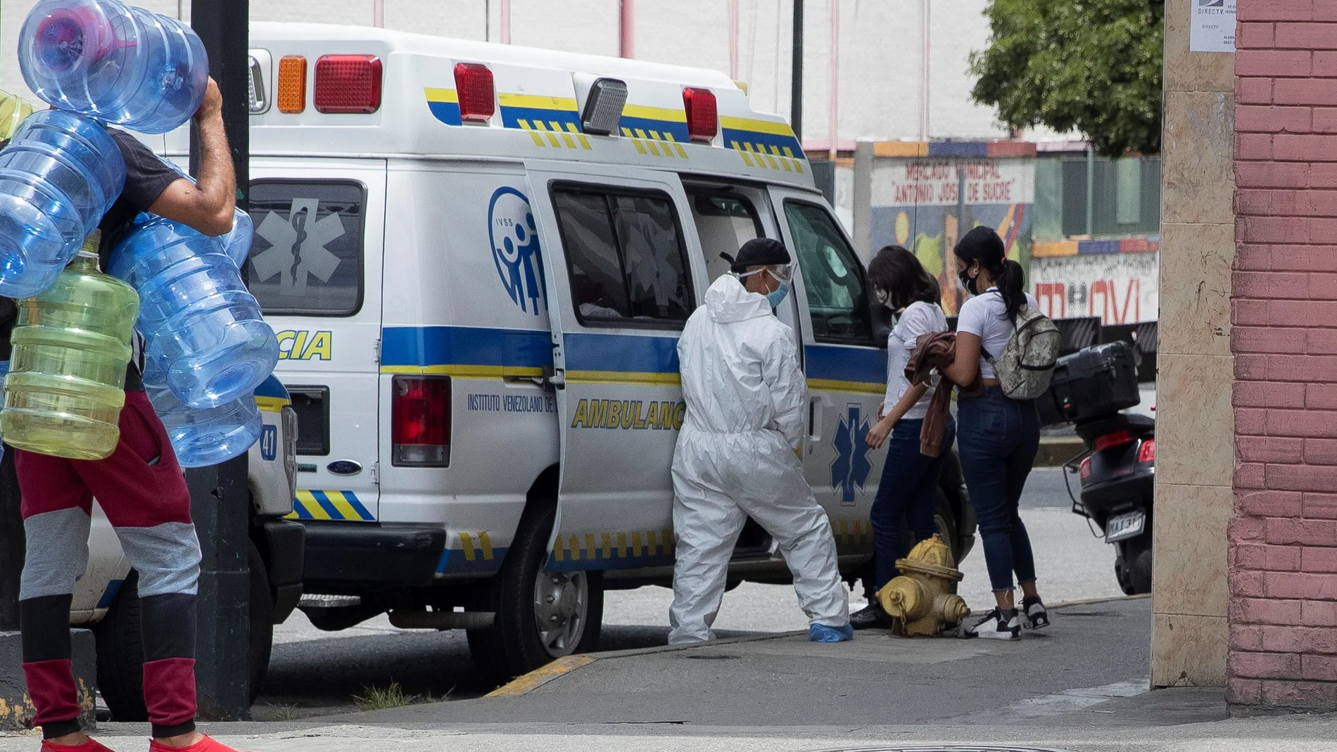 Un trabajado sanitario asiste a dos mujeres al ingresar a una ambulancia frente a la Clínica Popular de Catia, en Caracas (Venezuela).